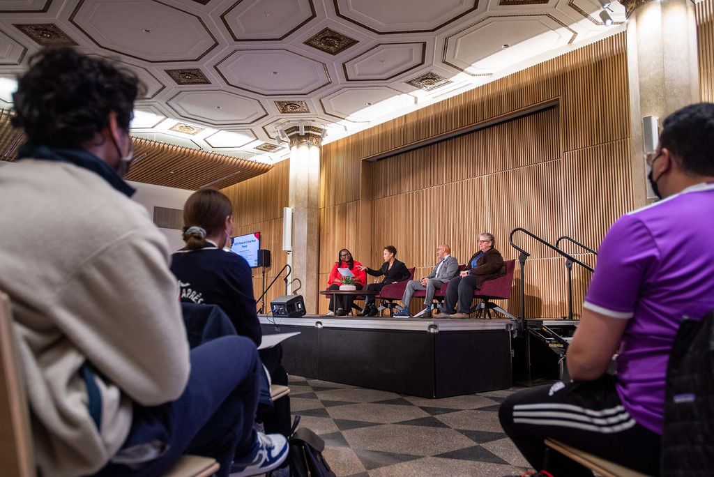 Photo of Moderator Angela Onwuachi-Willig, dean of LAW (from left), Janet Dewart Bell, LEAD InterGenerational Solutions founder and president, Craig Andrade, SPH associate professor of the practice, Laura M. Jiménez, Wheelock associate dean of equity, diversity, and inclusion, on stage at Critical Race Theory panel hosted by SDO at the Howard Thurman Center February 10. Audience members are seen sitting in the foreground.