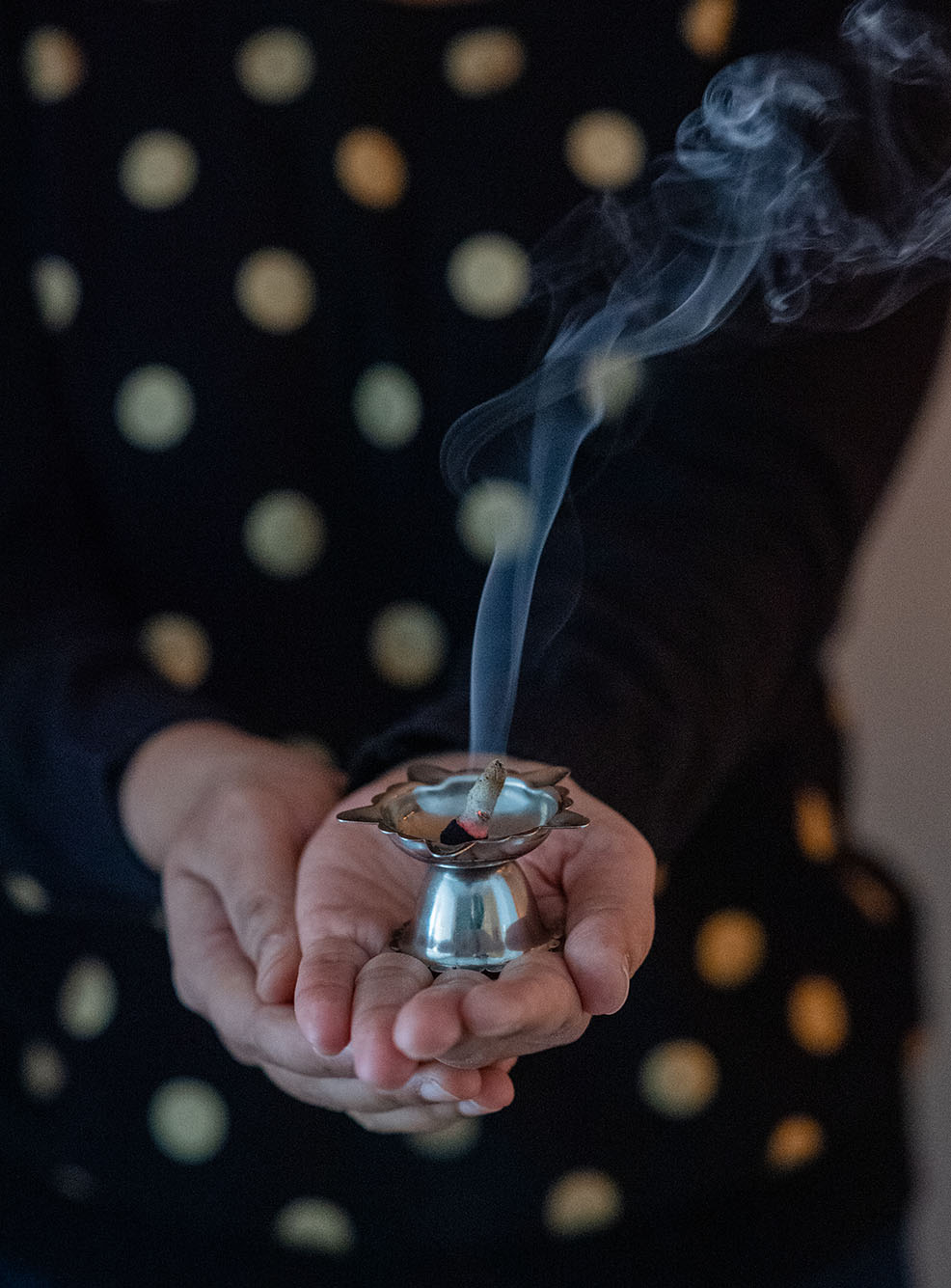 Photo of Swati Gupta's hands as she shows a metal holder with incense burning