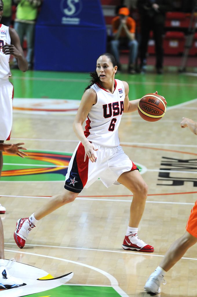 Sue Bird dribbles a basketball down the court; she was a US jersey with the number 6.