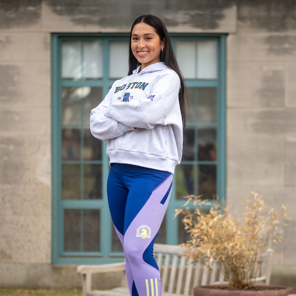 Yesenia Arango is raising money for Metro Housing|Boston, which strives to provide housing equity for all Bostonians. Here she stands in blue running pants and a sweatshirt