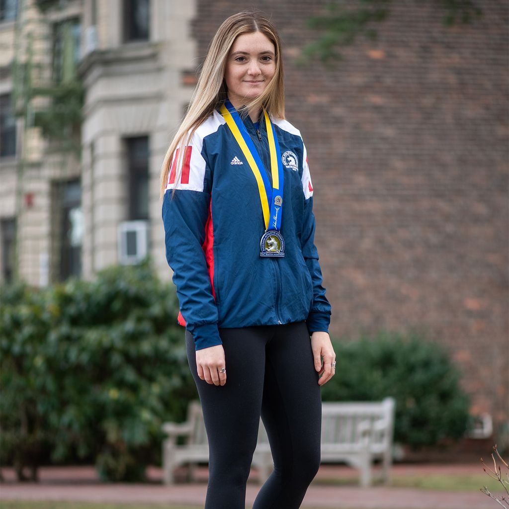 Cara Mooney’s grandfather, Frank Mooney, is something of a Massachusetts track and field coaching legend. She is raising money for her grandfather’s charity, the Mooney McIntyre Fund, which supports the Reggie Lewis Track and Athletic Center. Here Cara is wearing a Boston Athletic Association jacket as well as a medal
