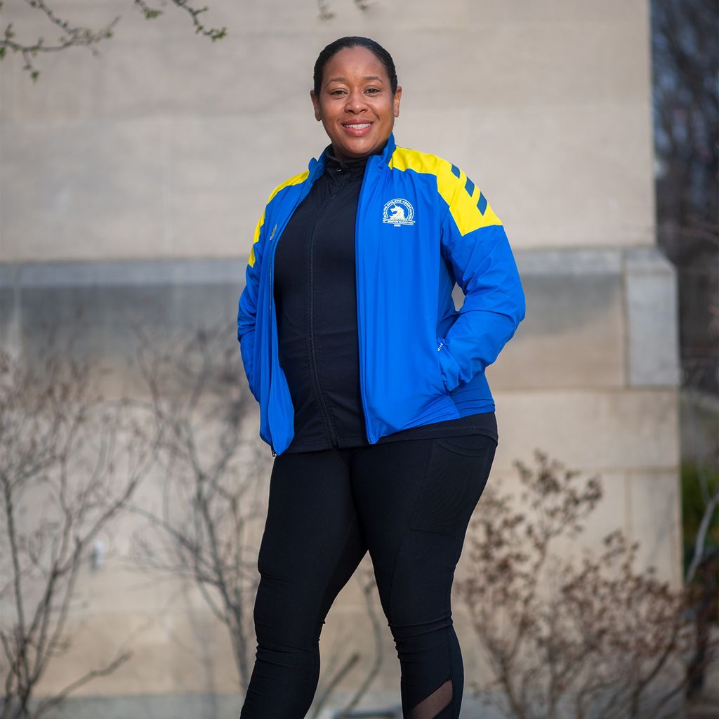 Olivia Clachar, Assistant Director of Payment Systems, Accounts Payable is running in the 2022 Boston Marathon, standing here in a blue marathon jacket and black pants