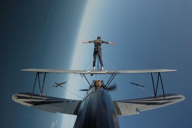 Ryan Loughran stands on the wings of a small plane while it flies