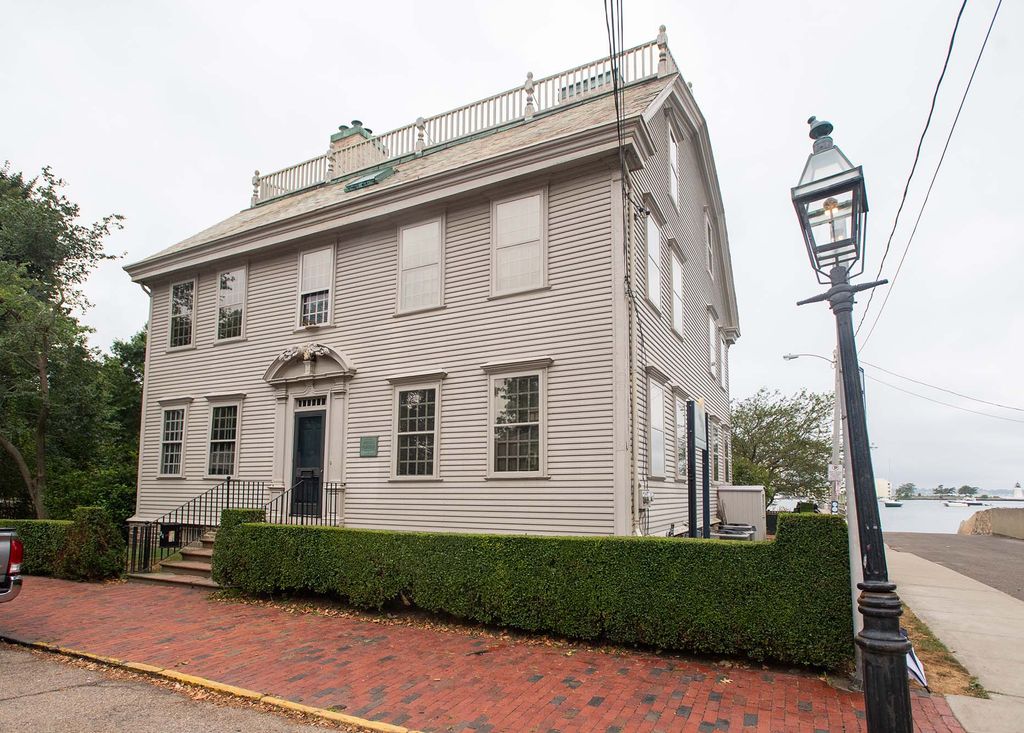 Photo: Exterior view of the Hunter House. A large, white house sits behind a brick walkway.