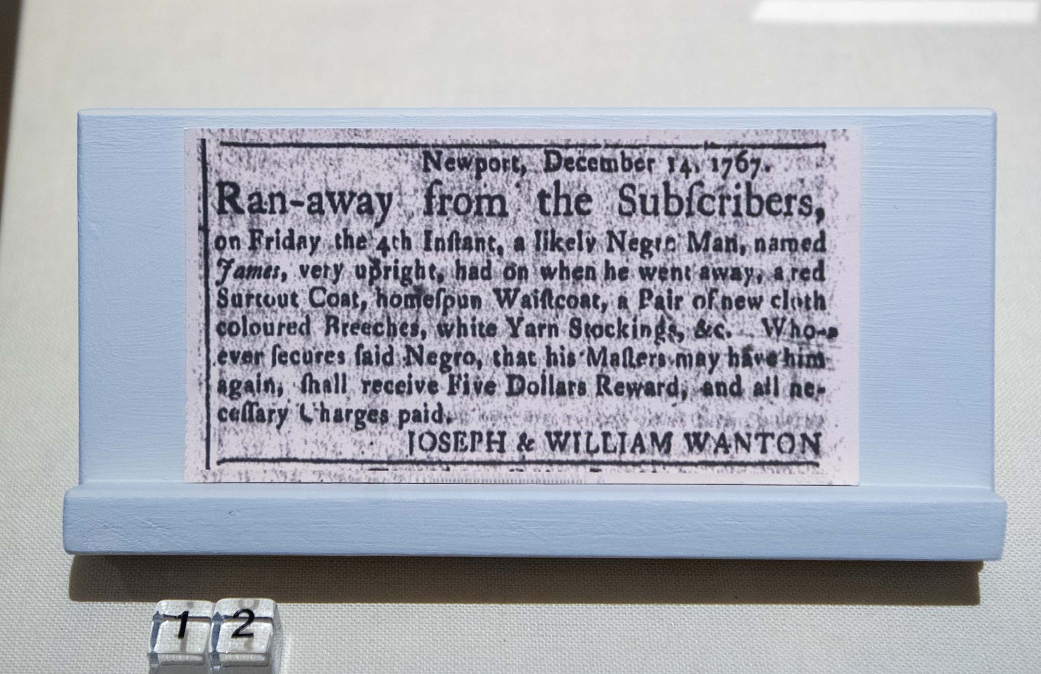 Photo: A framed runaway slave ad from the house. In large black text, the ad starts "Run-away from the Subscribers" and describes the enslaved person on parchment paper.
