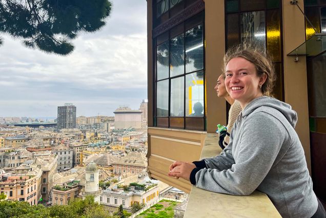 Photo: Tess Walsh (Wheelock’24) leans against a stone ledge and smiles and turns to the camera on her left. Another student to her right stares straight ahead. A distant scene of Padua, Italy can be seen from an overhead view to both students' lefts.