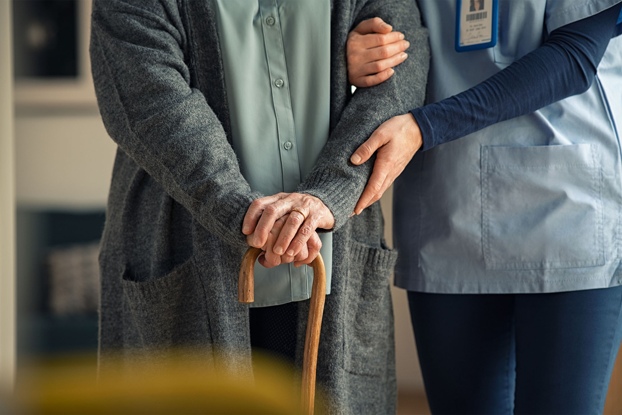 Close up hands of caregiver doctor helping old woman at private clinic. Close up of hands of nurse holding a senior patient with walking stick. Elder woman using walking cane at nursing home with nurse holding hand for support. Photo creds: Ridofranz/iStock