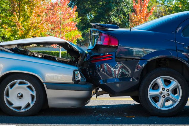 Photo: Close-up of a car accident involving two cars on a city street. The cards were in a "fender bender" and shows one car crashed into the rear end of another.