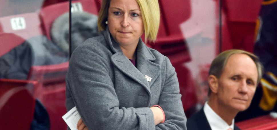 Photo: Tara Watchorn (Sargent’12), a white woman with short blonde hair standing with arms crossed behind the BU Women's Hockey bench in 2019-20, when she served as assistant women’s ice hockey coach, with longtime head coach Brian Durocher (Wheelock’78) an older white man wearing a suit and tie, standing to her right.