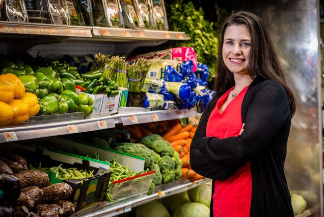 Photo: Boston University SAR Assistant Professor of Nutrition Maura Walker, a white woman wearing a red shirt and black cardigan, poses for a photo at Bazaar Supermarket in Cambridge on May 5, 2023. She is doing cutting-edge nutrition research on topics including the gut microbiome, precision nutrition, and nutrigenomics. Photo by Jackie Ricciardi for Boston University