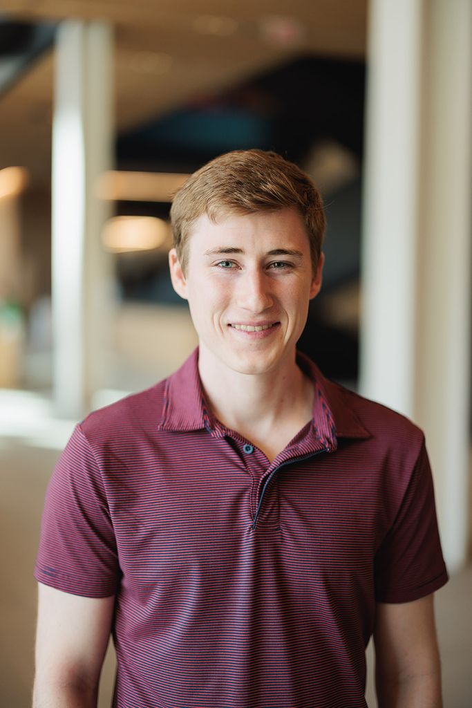 Photo: Daniel Skahill, a young white man with ash brown hair and wearing a burgundy shortsleeved collared shirt, smiles and poses for the camera.