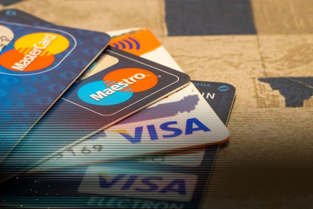 Photo: A pile of four credit cards, two from MasterCard and two from VISA, on a table.