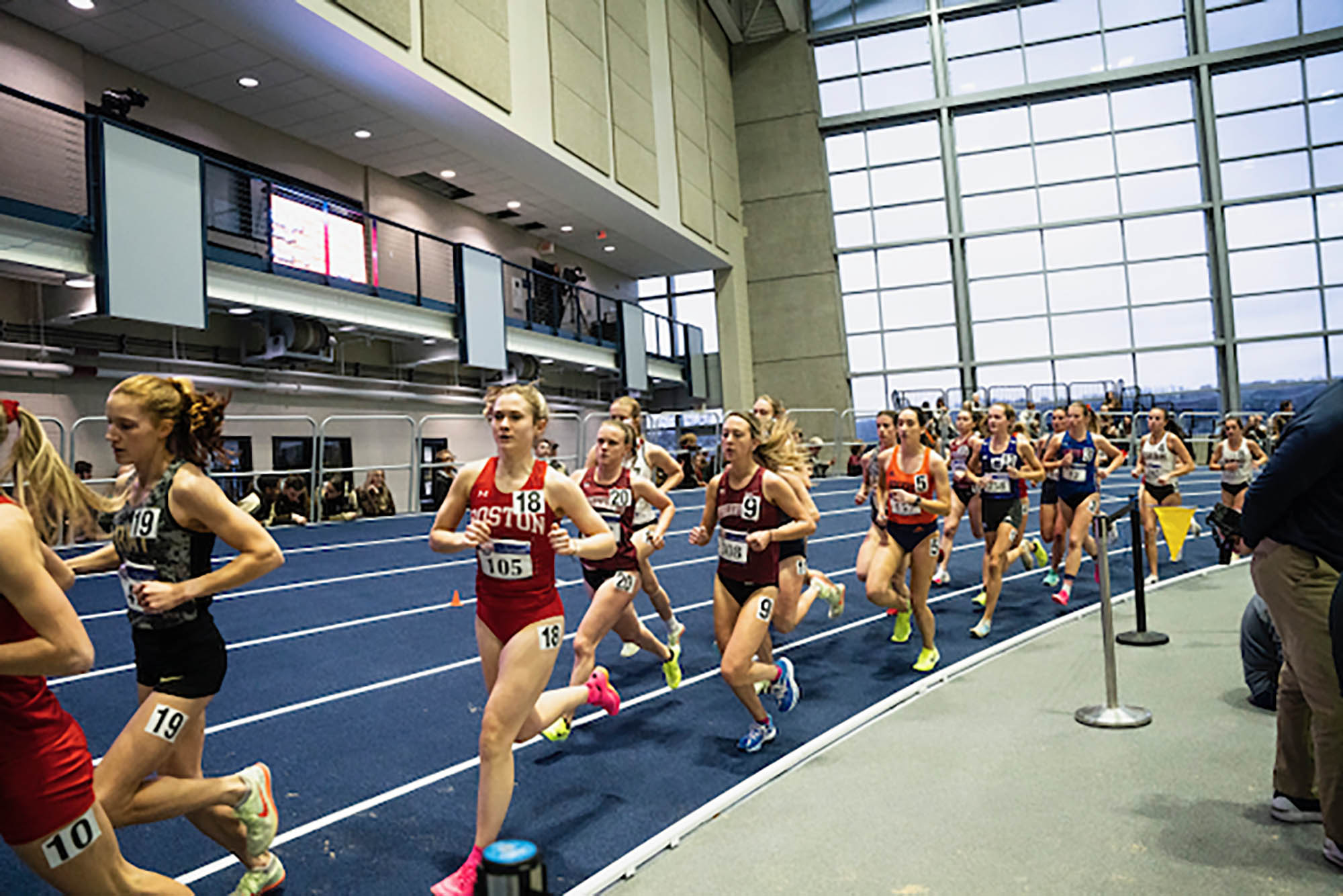 Photo: A group of runners speed by the camera as they race on an indoor track.