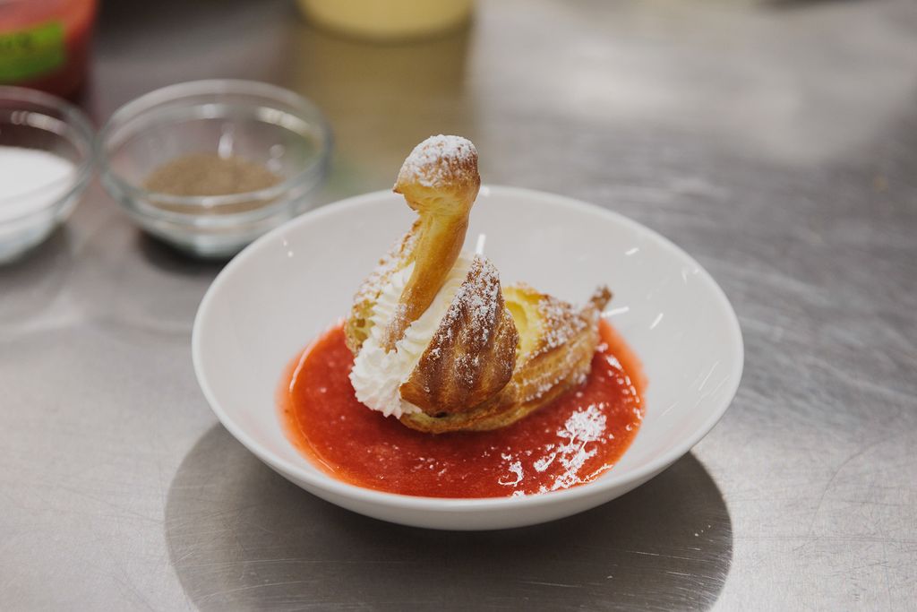 Photo: A pastry swan sitting on a bed of fruit compote in a white bowl made by Jacques Pepin at the BU Gastronomy Kitchens.