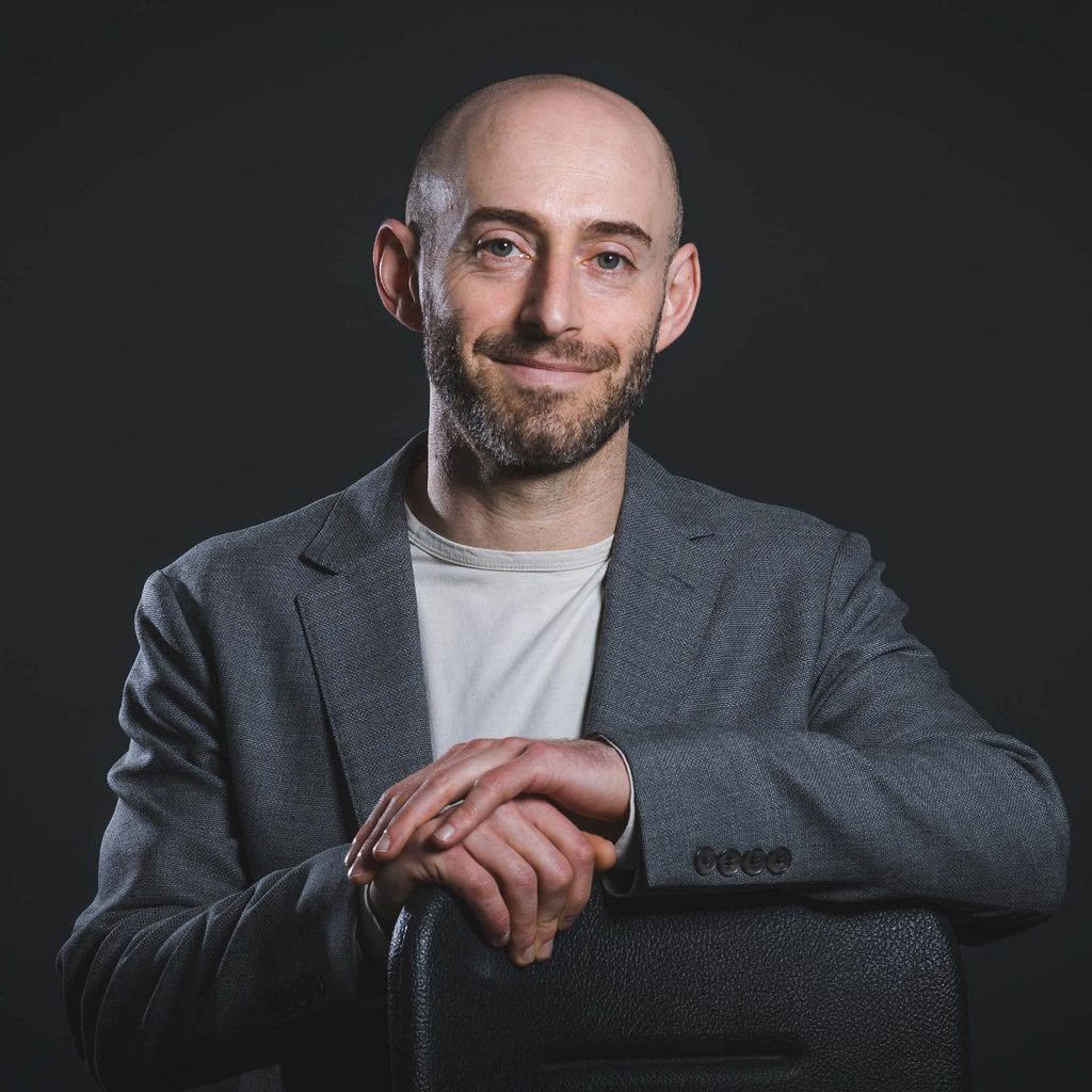 Photo: A bald man in a nice suit poses for a photo with a smile. Jonathan Feingold , Associate Professor of Law, poses for a photo on May 23, 2022. Photo by Jackie Ricciardi for Boston University