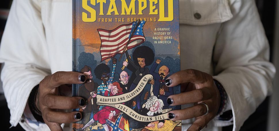 Photo: Two hands with black painted fingernails hold a copy of "Stamped from the beginning", a graphic novel adapted from Dr Ibram X Kendi’s book