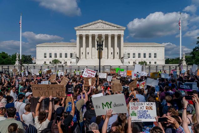 Photo: A crowd of protestors hold pro-choice signs as they protest and gather outside the fenced off Supreme Court.