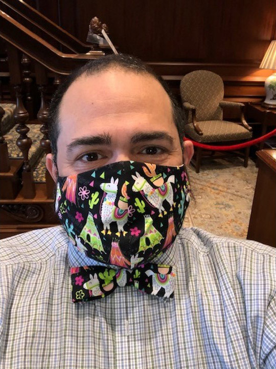 Photo of Jesus Nater with a mask and matching bowtie with a black, llama and cactus print mask and striped button down.