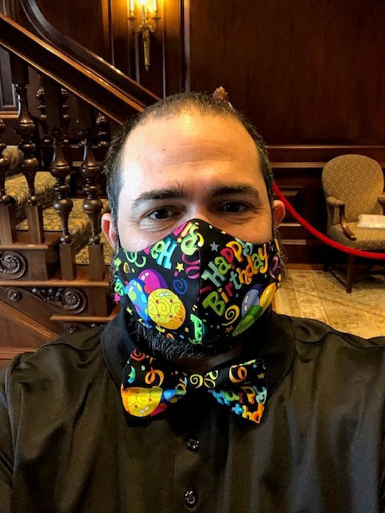 Photo of Jesus Nater with a mask and matching bowtie made black fabric, and a pattern that says "happy birthday" and balloons on it.