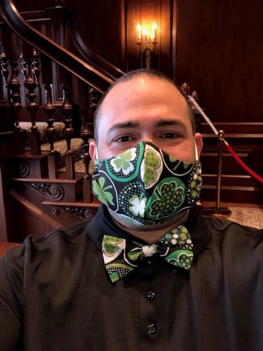 Photo of Jesus Nater with a matching mask and bowtie that have a black and green shamrock pattern.