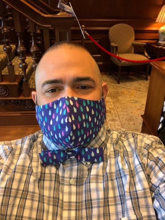 Photo of Jesus Nater with a matching mask and bowtie made with a dark blue fabric with small colorful rain drop shapes on it.