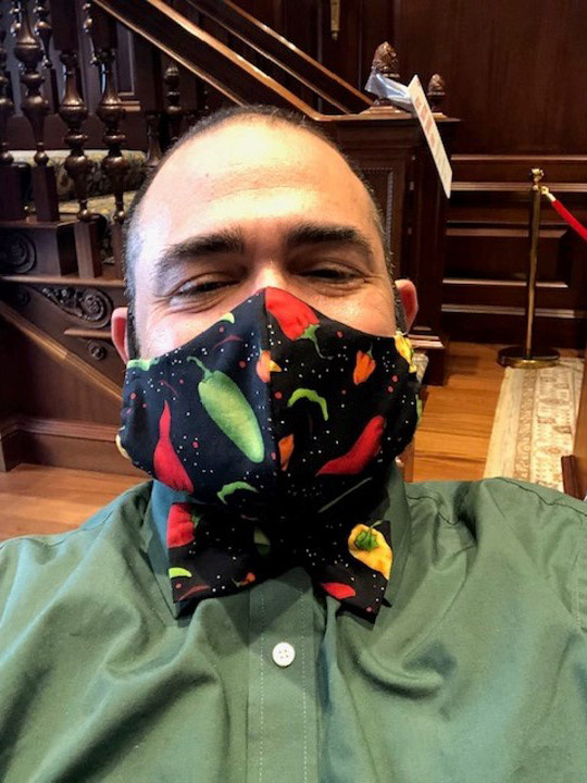 Photo of Jesus Nater with a matching mask and bowtie made with black fabric with a green and red chili pepper pattern on it.