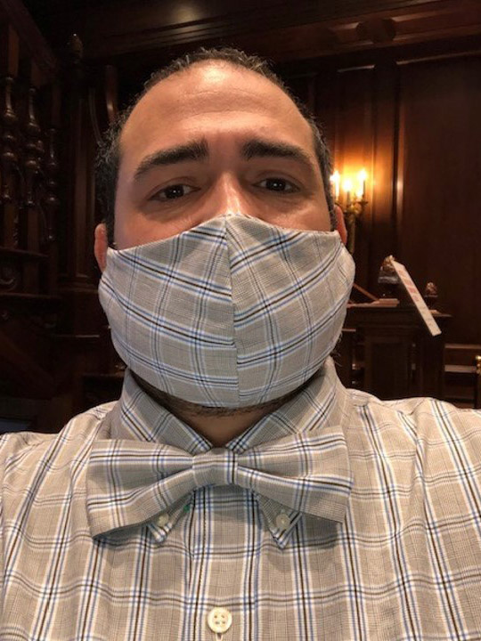 Photo of Jesus Nater with a matching mask, bowtie, and shirt with a blue and gray plaid pattern.
