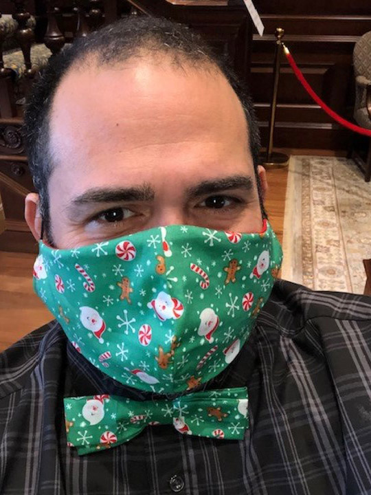 Photo of Jesus Nater with a matching mask and bowtie that is green with a santa and candy cane pattern on it.