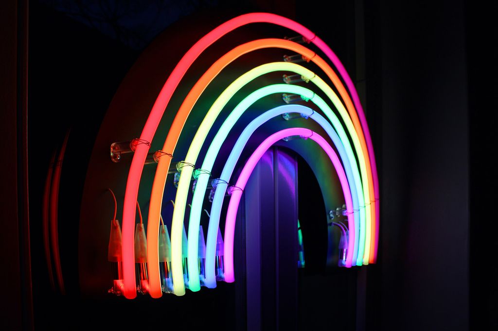 Photo: A neon sign of a rainbow, tilted to the right.