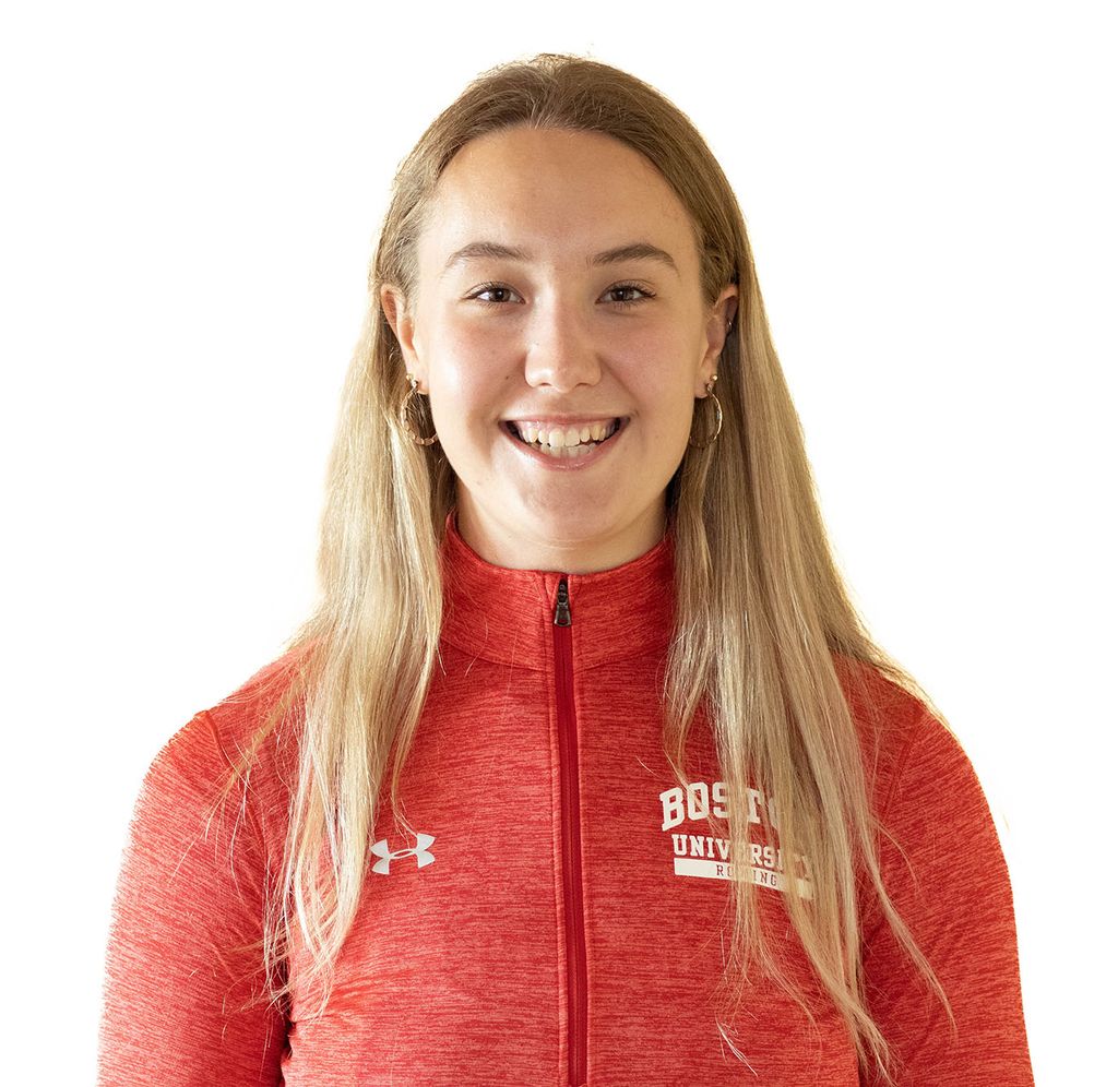 Photo: Headshot of Kat Robbins. A young white woman with long blonde hair and wearing a scarlet red Boston University pullover poses in front of a white background.