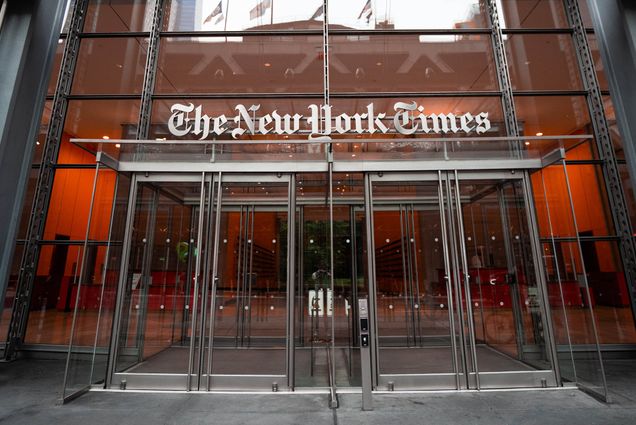 Photo: Exterior shot of the New York Times building. A glass building with glass doors is shown. Above the doors, silver letters that read "The New York Times" is shown.