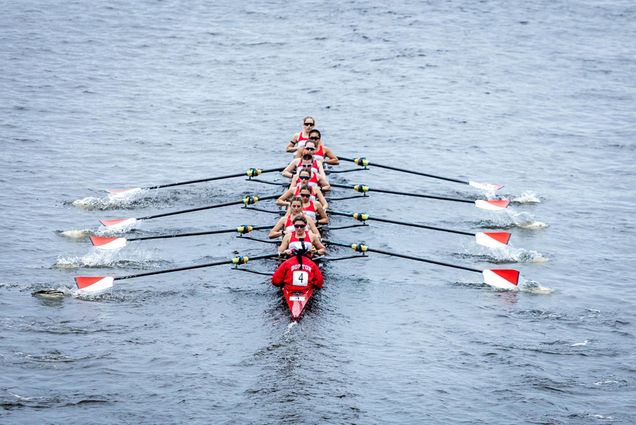 Photo: A group of athletes rowing a boat down a river