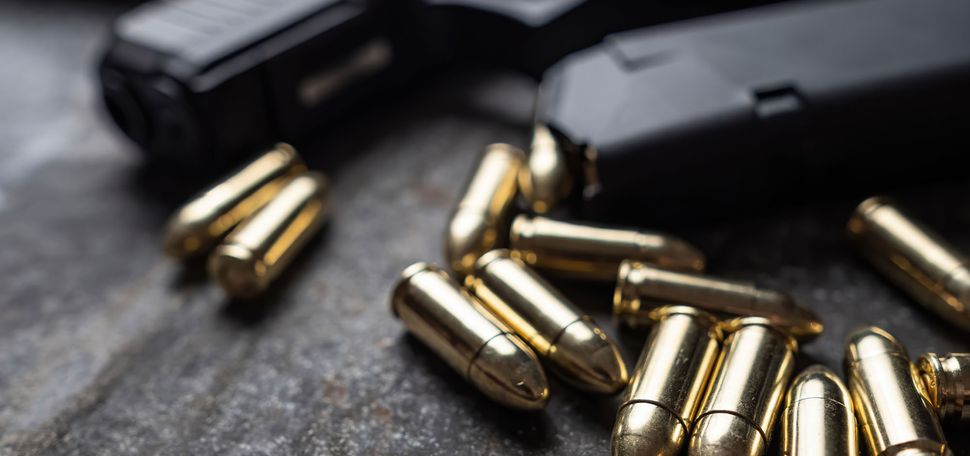 Photo: A handgun with bullets laying on a table