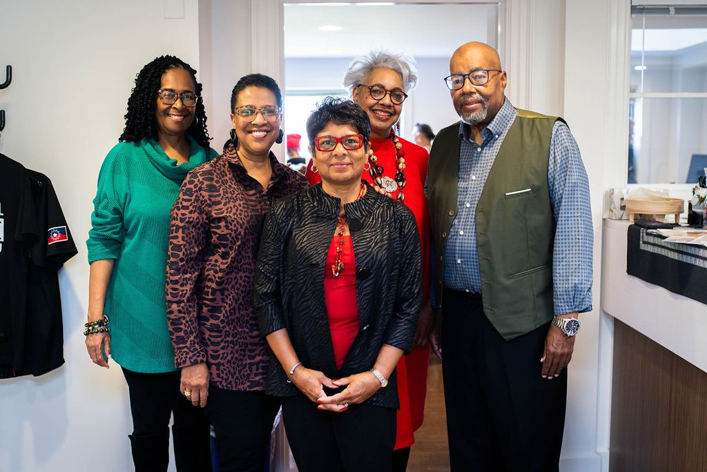 Photo: Five Black people wearing smart casual wear stand and pose for a photo together. From left to right: Alva Baker, Linda Keene, Sue Brown Peters, Beverly Headen-Moss, and Manfred Hayes.