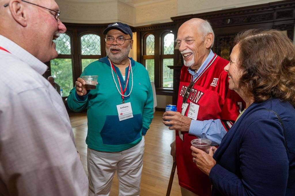 Photo: Four people mingle and chat in a small group. From left to right: Connell Tar (Questrom’73), Anthony Williams (CAS’75, Questrom’78), Jim Skerkas (Wheelock’73) and Ellen Skrekas.