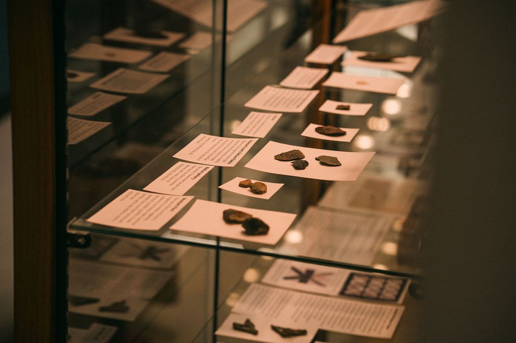 Photo: Glass display at Photo: A broken black vase is shown on display on a lack table at the new Mary C. Beaudry Community Archaeology Center. shows various old personal items such as combs, buttons, and pipes.