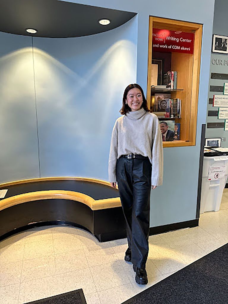 Photo: A student wearing a grey sweater and black pants poses for a full body portrait