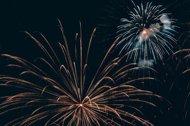 Photo: Two large red and blu fireworks are shown going off in a night sky.