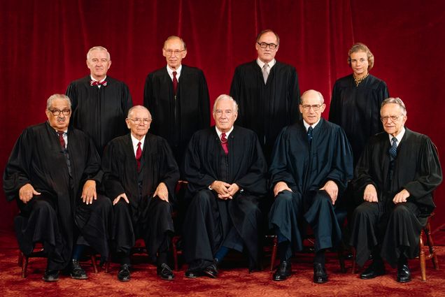 Photo: Group photo of the Supreme Court when Sandra Day O'Connor joined. A group of people wearing Black Supreme Court robes stand and sit in front of dark red curtain. The Justices are (left to right front row;) Thurgood Marshall; William J. Brennan Jr.; Chief Justice Warren Burger; Byron R. White; Harry A. Blackmun. (Back row, left to right;) John Paul Stevens; Lewis F. Powell, Jr.; William H. Rehnquist; Sandra Day O'Connor.