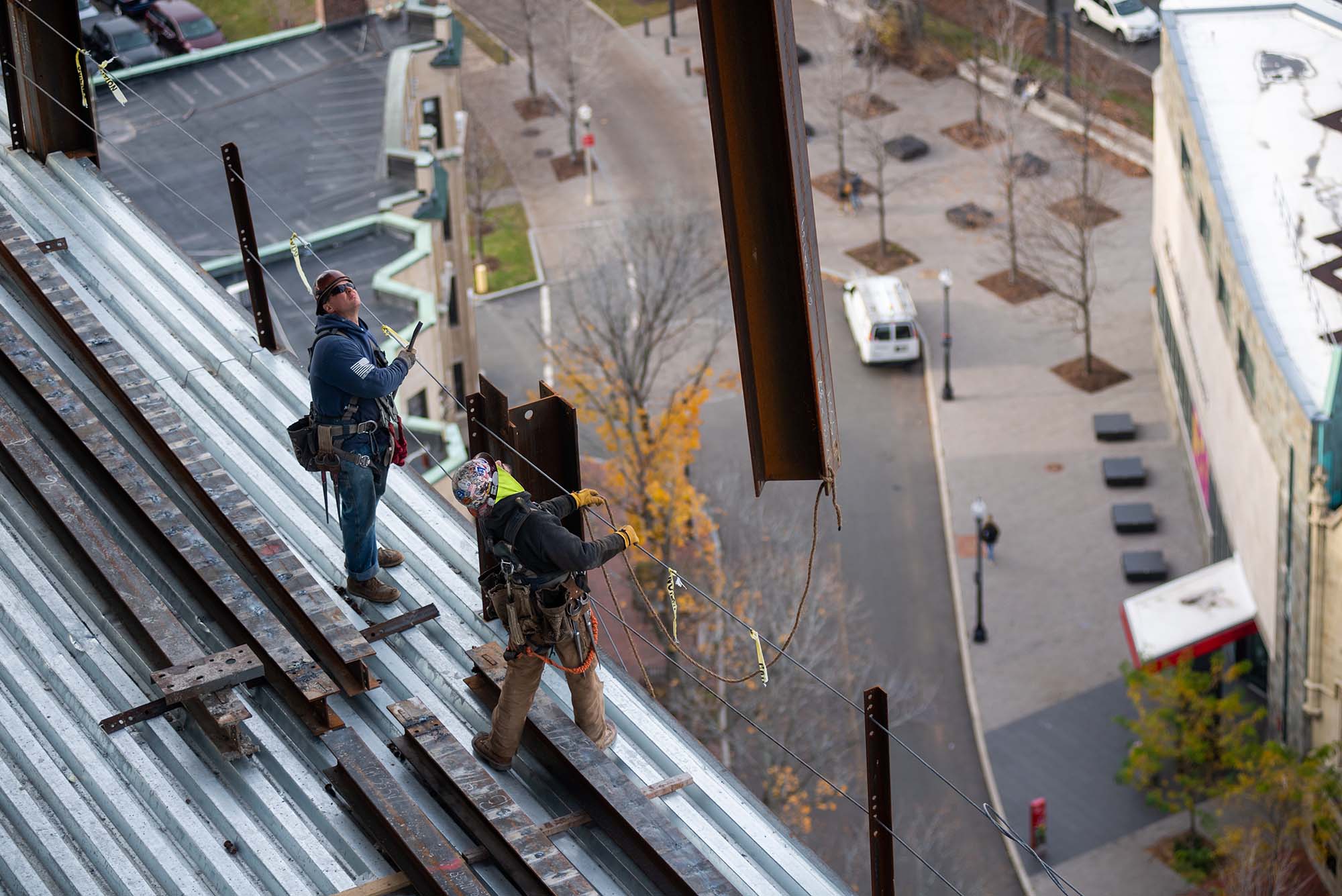 Photo of two construction workers watching as a beam is lifted off the data sciences center.