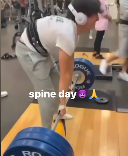 This is a meme of a person lifting weights at the gym. They have improper form while they are deadlifting, so the caption says "spine day." The person's back is arched inward an unhealthy amount.