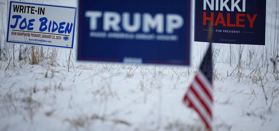 Photo: Two political lawn signs in a snowy yard, one for Trump and one for Nikki Haley, next to a sign endorsing Joe Biden for president as a write in.