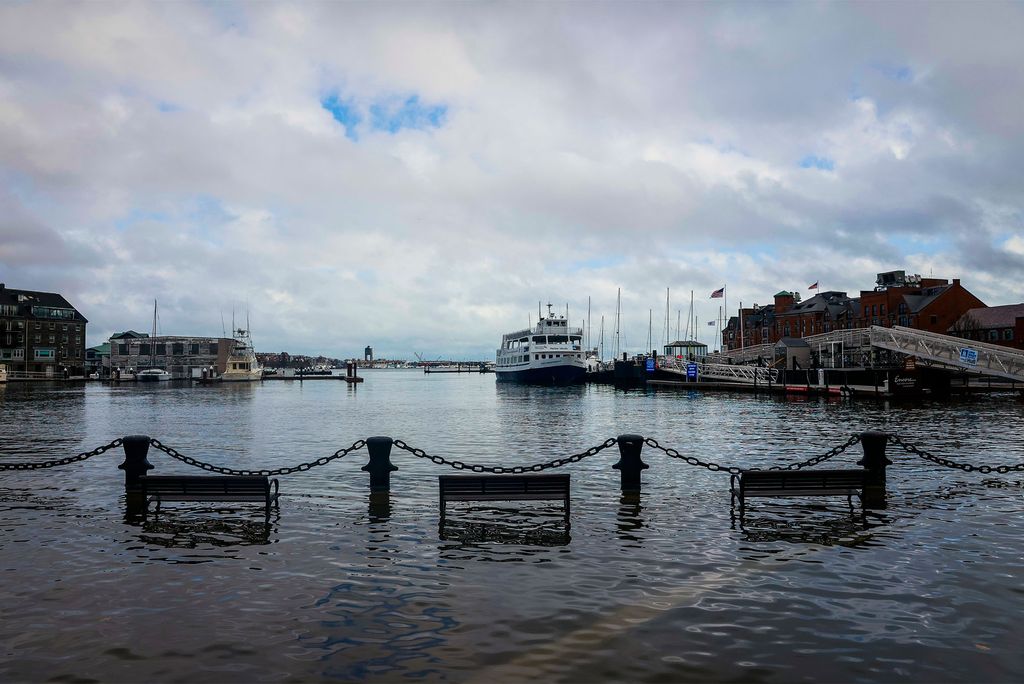 Photo: Flooding in Boston harbor shows benches covered in seawater up to the seat and a boat in the background