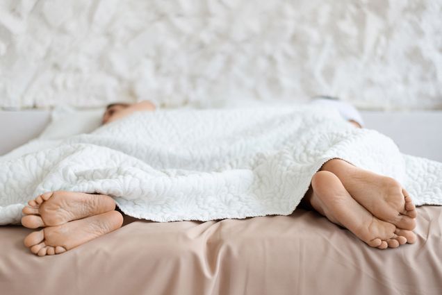 Photo: A stock photo with two people in the bed separate from each other with a white blanket.