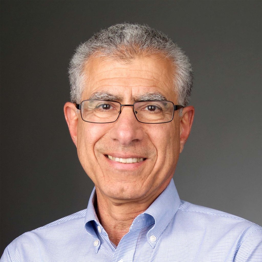 Photo: Closeup portrait headshot of a white man wearing glasses, with a smile