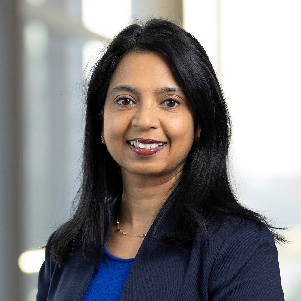 Photo: Portrait of Tuhina Neogi, a young South Asian woman with medium length dark hair and a bright smile.