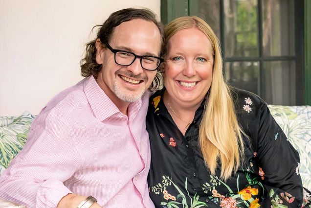 Photo: A man wearing glasses wearing a collared shirt sits next to a blonde woman with a smile and a darker shirt