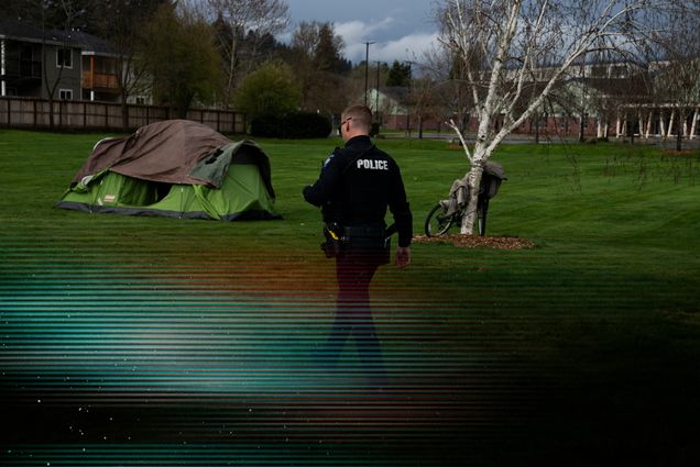 Photo: A picture of a man in a police uniform walking through a field that has a tent. There is a glitch overlay over the image