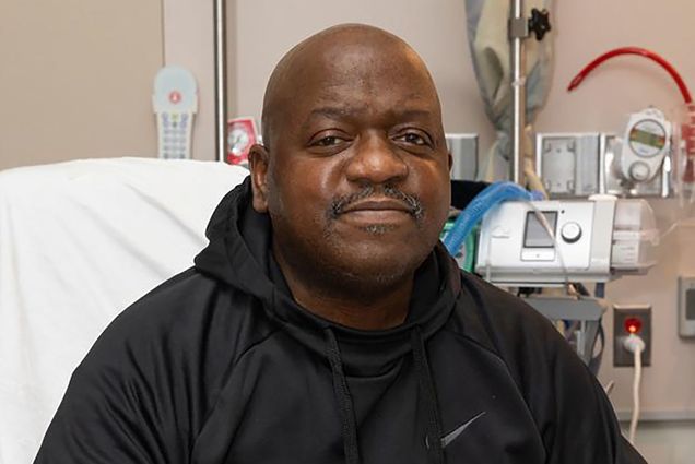 Photo: Rick Slayman, a Black man who was the first to receive a pig organ as a transplant, sits on his hospital bed with a black hoodie.