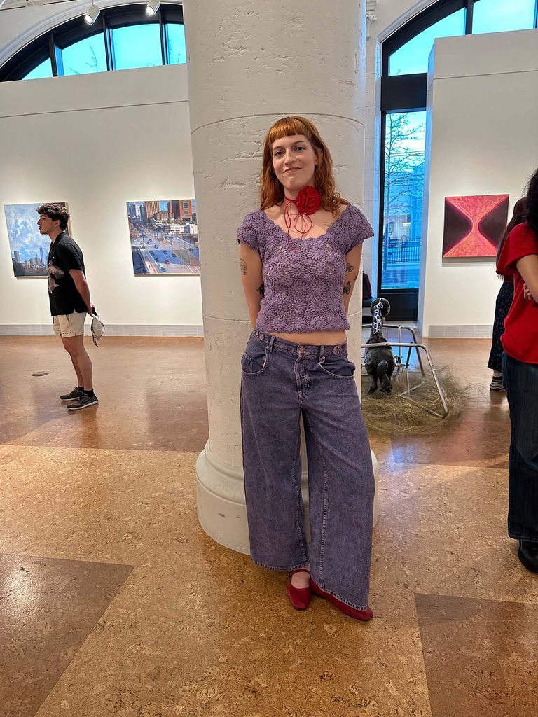 Photo: A picture of a girl with a purple floral patterned top with wide legged jeans and red ballet flats. She also is wearing a red necklace with a flower on it